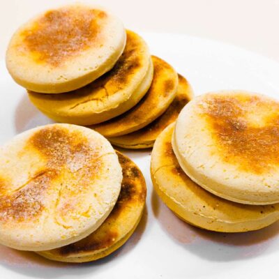 A front view of some delicious gluten free english muffins stacked up on a plate, ready to be eaten