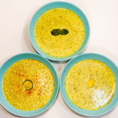 A top down view of 3 blue bowls containing an avocado soup