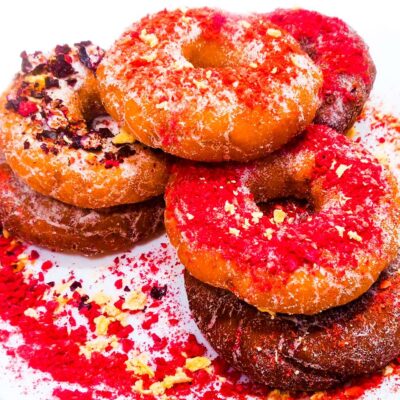 A side view of some gluten free and vegan donuts sitting on a plate, topped with dried fruits
