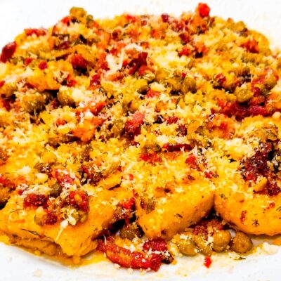 A front view of some gluten free ricotta gnocchi, topped with bacon and served on a plate